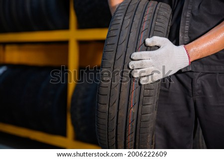 Asian male tire changer In the process of checking the condition of new tires in stock so that they can be replaced at a service center or auto repair shop. Tire warehouse for the car industry