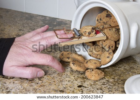 Hand stuck in a mousetrap after being tricked in the cookie jar Royalty-Free Stock Photo #200623847