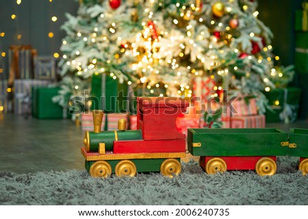 Red-green wooden train under the Christmas tree. Merry Christmas and happy new year concept. Selective focus