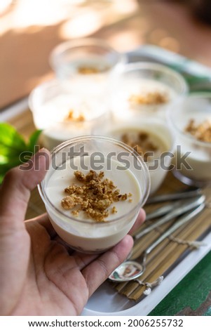 A portrait picture of homemade Japanese cheesecakes with regal topping served with a transparent cup on the bamboo sheet. It shoots in the morning after breakfast with high angle and eyes angle. 