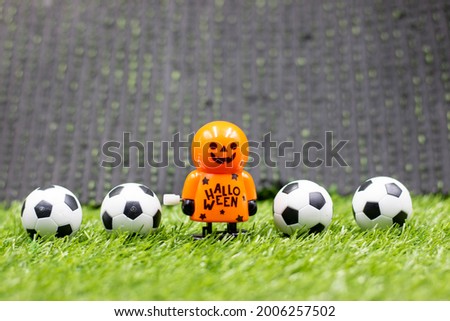 Ghost is playing football on Halloween Day on green grass