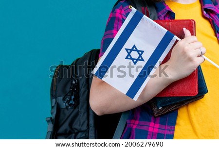 Young girl with school stuff holds in hand Israel flag close up