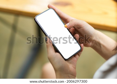 Close up of female hands browsing, using, paying, holding on smartphone with blank screen, blurred background