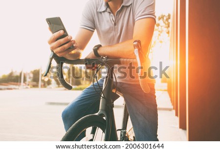 The young guy surfing the net while leaning at his bicycle