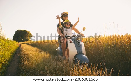 The father and son riding together through the field by pathway on the retro scooter Royalty-Free Stock Photo #2006301665