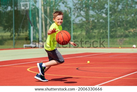 BOY RUNNIG WHILE PLAYING BASKETBALL DURING DOING SPORT IN THE PLAYGROUND AT SPORT AREAL Royalty-Free Stock Photo #2006330666