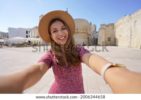 Proximity tourism concept. Smiling woman taking self portrait in Apulia with the old town of Otranto on the backgorund, Italy