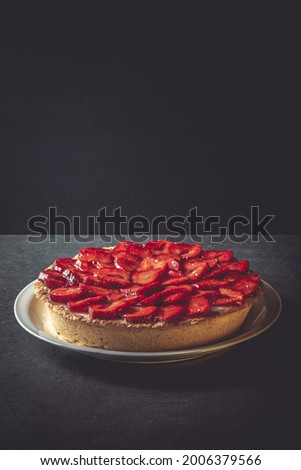 Homemade strawberry pie with syrup on a ceramic platter.