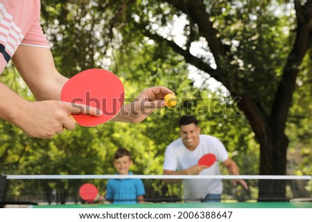 Family with child playing ping pong in park, closeup Royalty-Free Stock Photo #2006388647