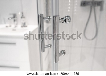 Close-up of chrome handles in a glass shower door. Modern bathroom interior. Royalty-Free Stock Photo #2006444486
