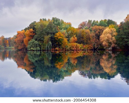 Bright autumn forest is reflected in the smooth water of the lake   