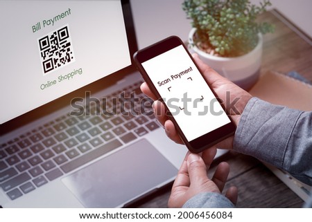 close up customer hands holding smartphone to scan payment with Online shopping website on laptop computer screen. concept of digital payment and online shopping vintage tone background.
