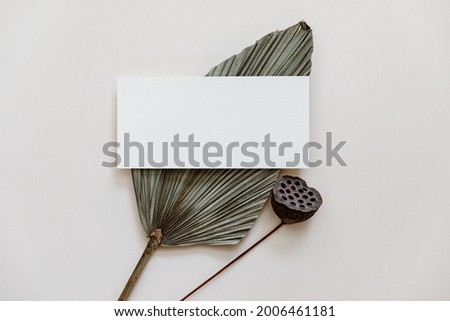 Minimal Summer stationery still life scene. Mock up with blank card and tropical palm leaf on beige neutral background. Blank greeting card, wedding invitation mockup scene 