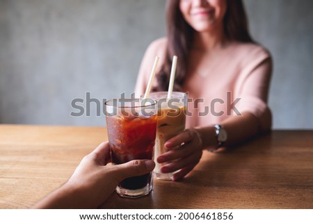 Closeup image of a couple people clinking coffee glasses in cafe