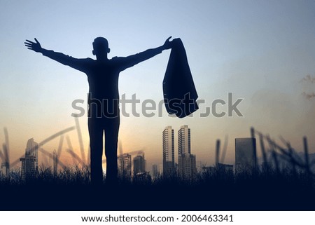 Silhouette of a businessman standing and raised hands with cityscapes background