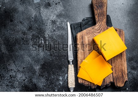 Slices of Cheddar Cheese on a wooden cutting board. black background. Top view. Copy space Royalty-Free Stock Photo #2006486507