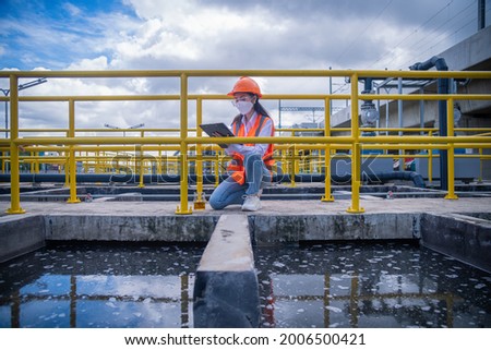Worker under checking the  waste water treatment pond industry large to control water support industry ,wearing mask for protect for virus and pollution. Royalty-Free Stock Photo #2006500421