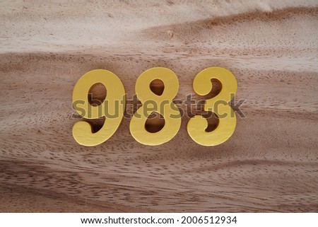 Gold numerals 983 on a dark brown to off-white wood pattern background.