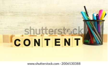 Seven stacked wooden cubes with letters CONTENT on a white work table on a gray background. Business concept