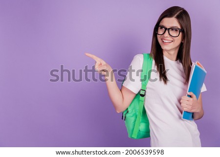 Photo of college student girl hold copybooks bag point finger empty space isolated purple background