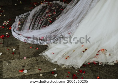 Tail of the wedding dress mixed with rose petals at the exit of the church