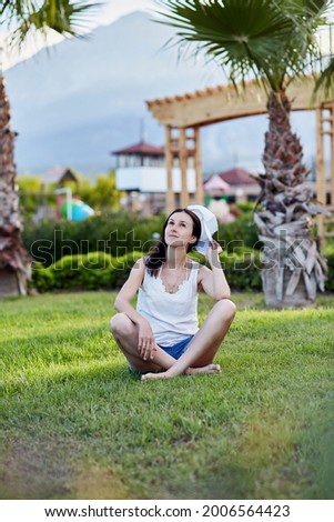 A young girl sits on the lawn and practices breathing exercises. Meditation, breathwork concept, oxygen training. High quality photo