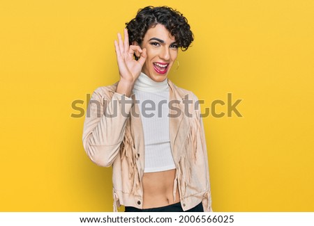 Handsome man wearing make up and woman clothes smiling positive doing ok sign with hand and fingers. successful expression. 