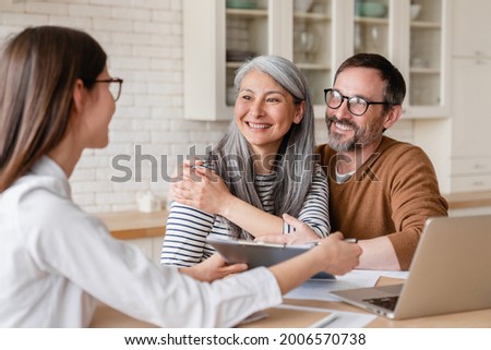 Successful positive deal. Lawyer financial advisor helping consulting showing contract mortgage loan credit business startup, signing documents by matute middle-aged couple at home Royalty-Free Stock Photo #2006570738