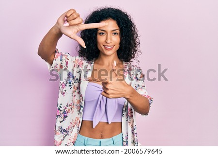 Young latin girl wearing casual clothes smiling making frame with hands and fingers with happy face. creativity and photography concept. 