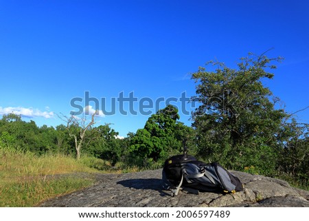 Swedish landscape view during the summer. Green nature and blue sky. Gray and black backpack paclsack in the front of the picture. Concept of free living. Sunny day outside. Stockholm, Sweden, Europe.