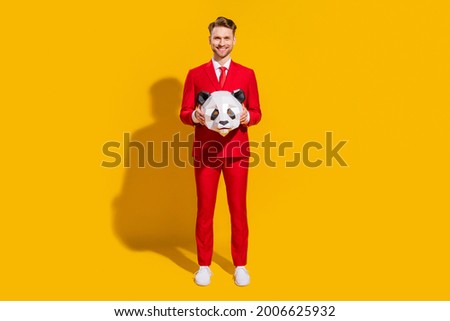 Photo of cheerful handsome blond guy hold panda mask wear red tuxedo tie isolated on yellow color background
