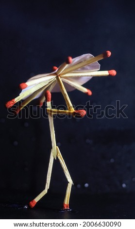 A matchstick man with a matchstick umbrella in the rain. Raining concept. Matchstick art photography used matchsticks to create the character. Royalty-Free Stock Photo #2006630090