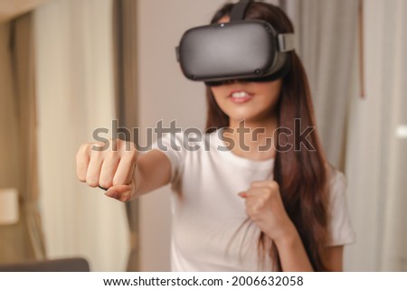 Happiness asian young woman wearing VR headset or visual reality goggles, glasses or gadget. Girl play videogame of simulator future,futuristic while wearable. Technology of modern concept.