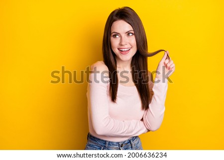 Photo of optimistic brunette lady hand hair look empty space wear pink shirt isolated on yellow color background