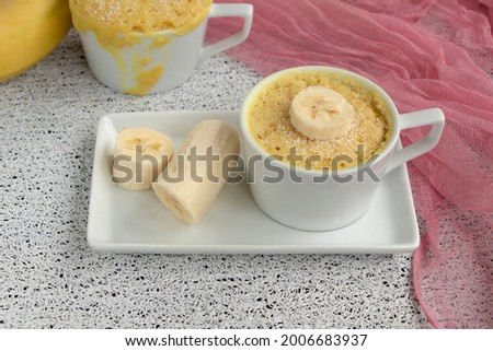 cupcake in a mug with banana pieces. Banana cupcake on a light background. The concept of a dessert in the microwave. bananas cake. High quality photo Royalty-Free Stock Photo #2006683937