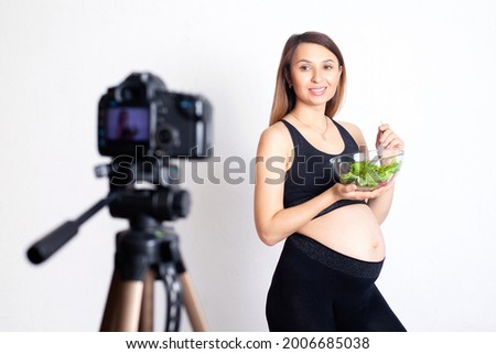 A pregnant woman blogger records a video on camera about proper nutrition during pregnancy. Sport and health. vegetarian. High quality photo