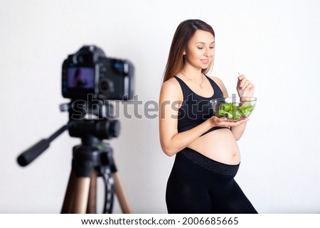 A pregnant woman blogger records a video on camera about proper nutrition during pregnancy. Sport and health. vegetarian. High quality photo