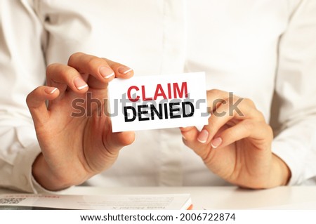 a woman in a white shirt holds a piece of paper with the text: claim denied. business concept