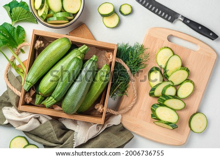 Slicing zucchini on a cutting board. Ripe zucchini on a gray background. Top view, horizontal. Royalty-Free Stock Photo #2006736755