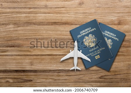 two Armenian  passport and airplane model on a wooden board 
