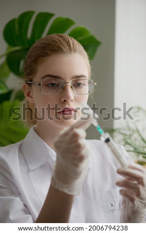 Woman in medical uniform with injection syringe in hand. Doctor or nurse at work. Scientists and science concept. Close-up, selective focus