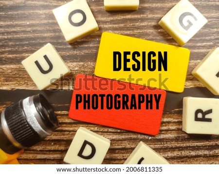 Business concept.Text DESIGN PHOTOGRAPHY on color board with toys latter and camera on wooden background.