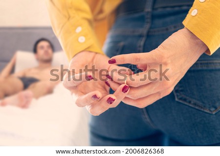a woman to remove wedding ring from her finger holding hands behind his back. remove the ring from your finger. The concept of treason and betrayal. Divorce and promiscuity. Royalty-Free Stock Photo #2006826368
