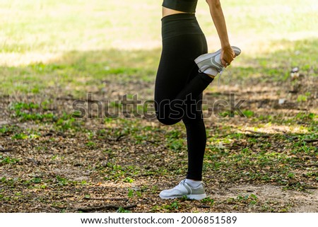 Asian woman wearing tight exercise clothes are doing worm up exercises in Green garden