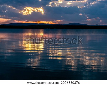 multi-colored blue and orange sunset sky over the lake, a fantastic picture of clouds, reflections on calm water, the southern Urals, lake Uvildy