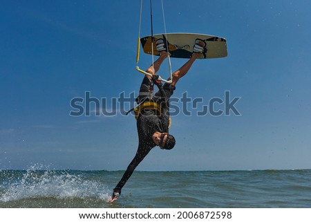 Kite surfer jumps with kiteboard  and doing "Hand drag"