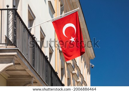The Turkish flag is fluttering on the wall of the building against the blue sky