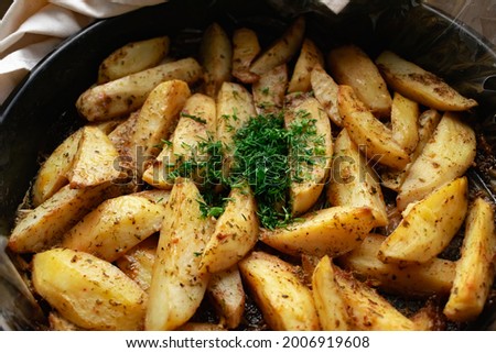 Aromatic baked potato wedges with fresh dill herbs.  Homemade rustic dish, delicious hearty food close up