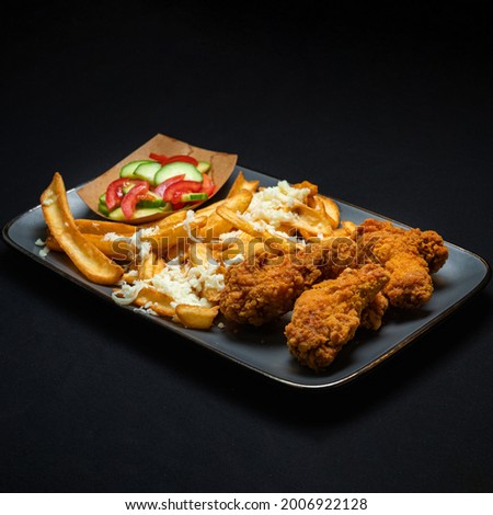 Menu with spicy wings, french fries and vegetable salad on a black background.