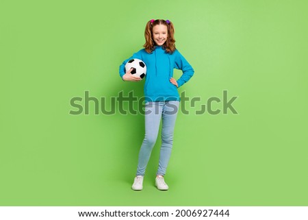 Full size photo of cheerful young happy girl hold hands football smile active isolated on green color background